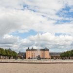 Blick auf das Schloss Schwetzingen gesehen vom Schlossgarten, im Vordergrund ist ein Wasserbecken mit Springbrunnen.