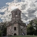 Merkurtempel im Schlossgarten im Gegenlicht aufgenommen. Die Mauern sind aus groben Steinen aufgeschichtet.