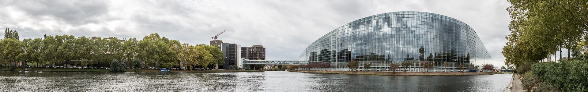 Das Europaparlament in Straßburg liegt am Wasser, in der verspiegelten Fassade spiegelt sich die Umgebung.